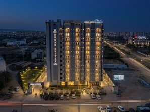 A multi-story hotel with a prominent entrance and a parking area. - Urban Suites by BluSalzz Rajasthan (Jaipur)