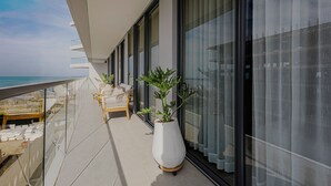 Un balcón con vistas al mar, una planta en maceta y una silla de mimbre.