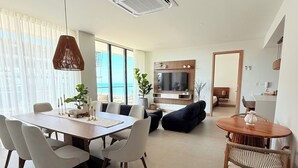 Una sala de estar moderna con comedor, televisor y vista al mar.
