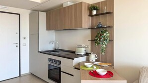 Une cuisine compacte équipée d’un four encastré, d’un évier et d’un petit coin repas avec une table dressée pour deux personnes.