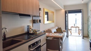 Une cuisine moderne dotée d’une cuisinière intégrée, un coin repas avec une table et des chaises, un canapé et un grand miroir mural.