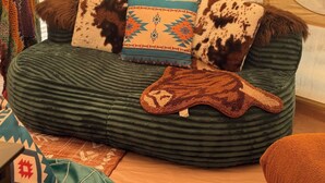A green upholstered sofa with patterned cushions and a decorative throw. - Pasture Bedtime Yurt (Middleburg)
