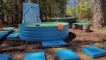 Une piscine circulaire recouverte d’une bâche bleue, avec un petit panier orange à proximité.