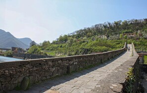 A stone bridge with a stone wall on one side and a pathway leading to a hillside with buildings. - 2 bedroom awesome home in Gioviano (Gioviano)