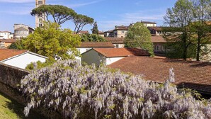 Un quartier résidentiel à l’architecture traditionnelle, comprenant une tour et une église, entouré d’arbres et de maisons aux toits recouverts de tuiles rouges.