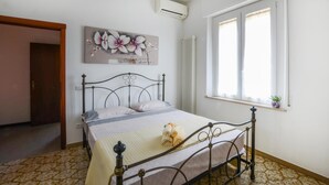 A bedroom with a bed, a radiator, a window, and a door. - Appartamento Casale Le Risaie (Vicopisano)
