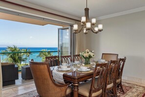 Un coin repas avec une table dressée pour six personnes, donnant sur un balcon avec vue sur l’océan.
