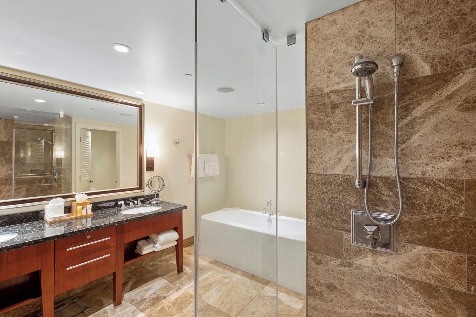 A modern bathroom with a glass shower enclosure, a bathtub, and a vanity with a large mirror.