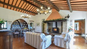 A rustic interior with a fireplace, wooden beams, and a dining area. - Umbria Magione Podere C. (Magione)