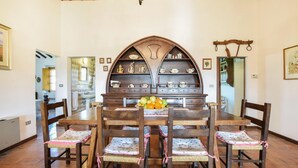 A dining room with a wooden table, six chairs, and a central decorative piece with shelves. - Umbria Magione Podere C. (Magione)