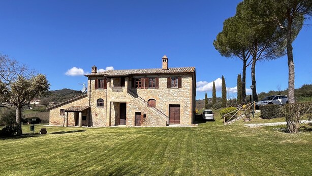 A stone house with a sloped roof, a central entrance, and a staircase leading to the upper floor. - Umbria Magione Podere C. (Magione)