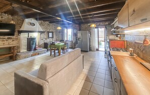 Eine rustikale Küche mit Steinwand, Holzboden und einem Essbereich mit grüner Tischdecke.