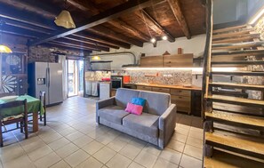 Eine gemütliche Küche mit Essbereich, einer Couch mit Kissen und einer Treppe mit Holzbeschlägen.