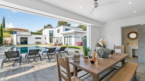 Un'area esterna moderna con zona pranzo, piscina, sedie a sdraio e vista sugli edifici circostanti.