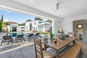 A modern outdoor dining area with a pool, lounge chairs, and a view of the surrounding buildings. - Maison de l’Esterel 5 BR - Private Pool, Frejus, France (Frejus)