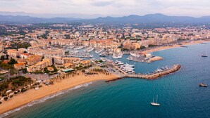 Una vista aerea di una città costiera con un porto turistico, spiagge sabbiose e edifici residenziali.