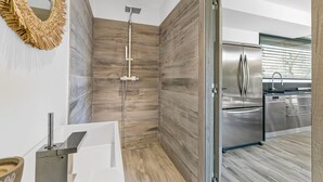 Un bagno moderno con doccia, uno specchio grande e un angolo cottura dotato di elettrodomestici in acciaio inossidabile.