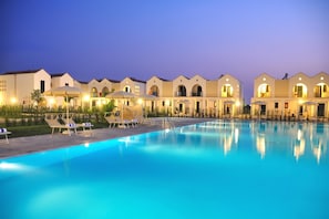 Ein Hotel mit Schwimmbad, Liegestühlen und Sonnenschirmen.