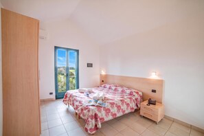 Ein Schlafzimmer mit Bett, Nachttisch und Blick durch eine Tür.