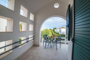 A balcony with a table and chairs, a view of the neighborhood, and a green door. - Beach in 5 min | Pool Access | n.66, Otranto, Italy (Otranto)