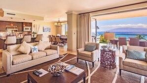 Habitación de hotel con sala de estar, comedor y balcón con vista al océano.