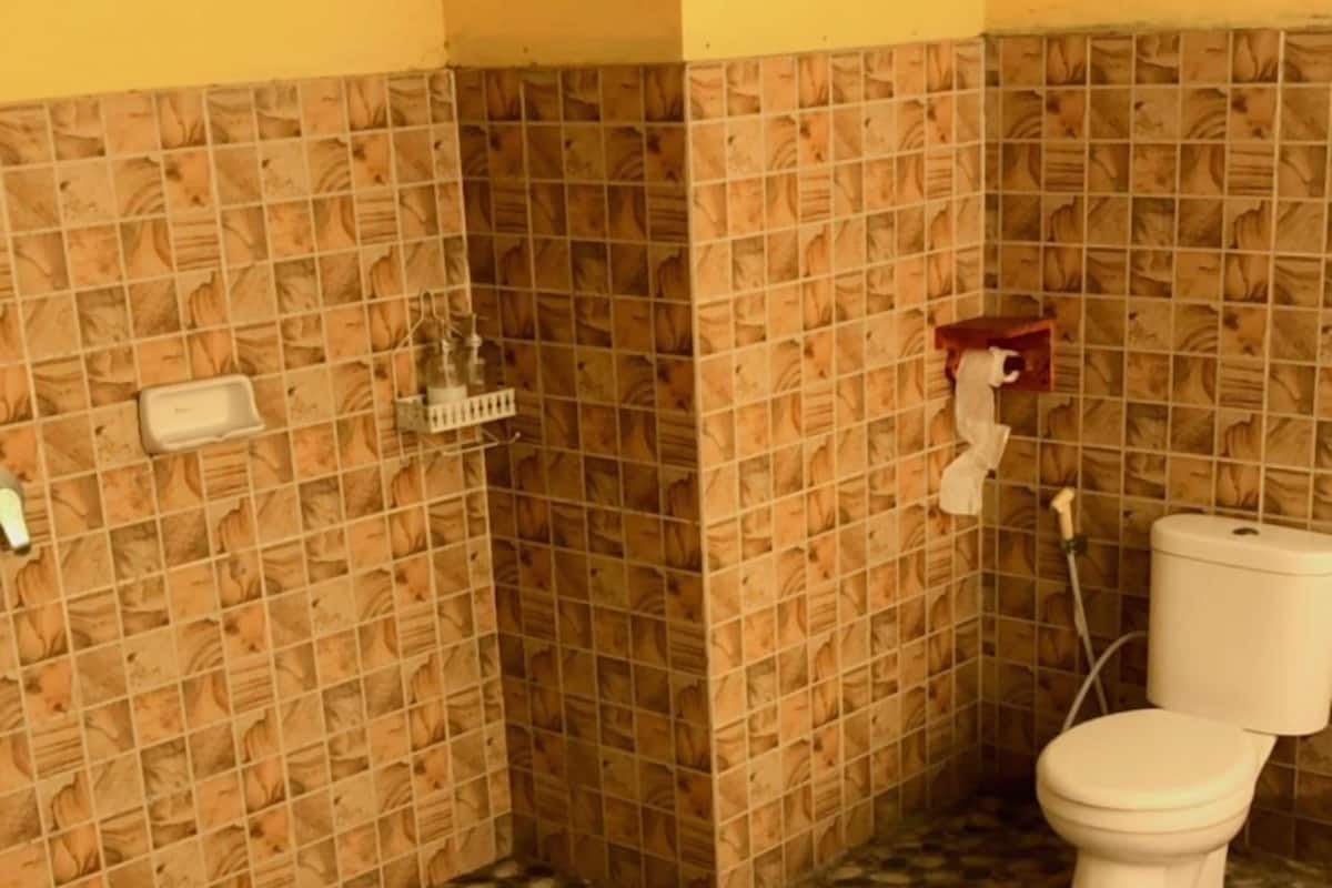 A bathroom with a tiled floor, a toilet, and a shower area.