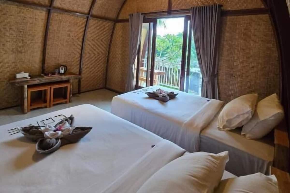 A dome-shaped room with two beds, a small table, and a window with curtains.