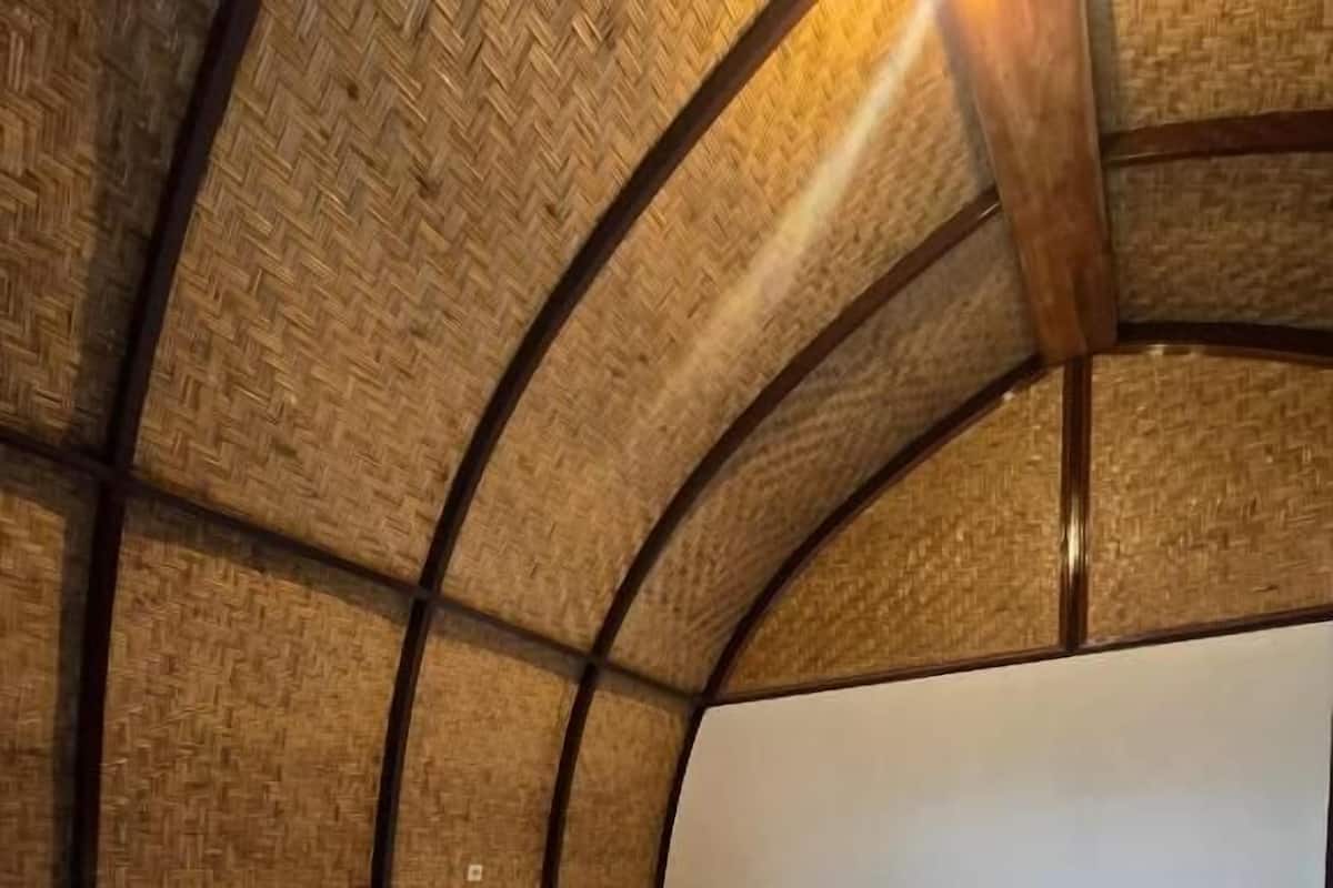 A room with a curved ceiling, a bed with white linens, and a wooden headboard.