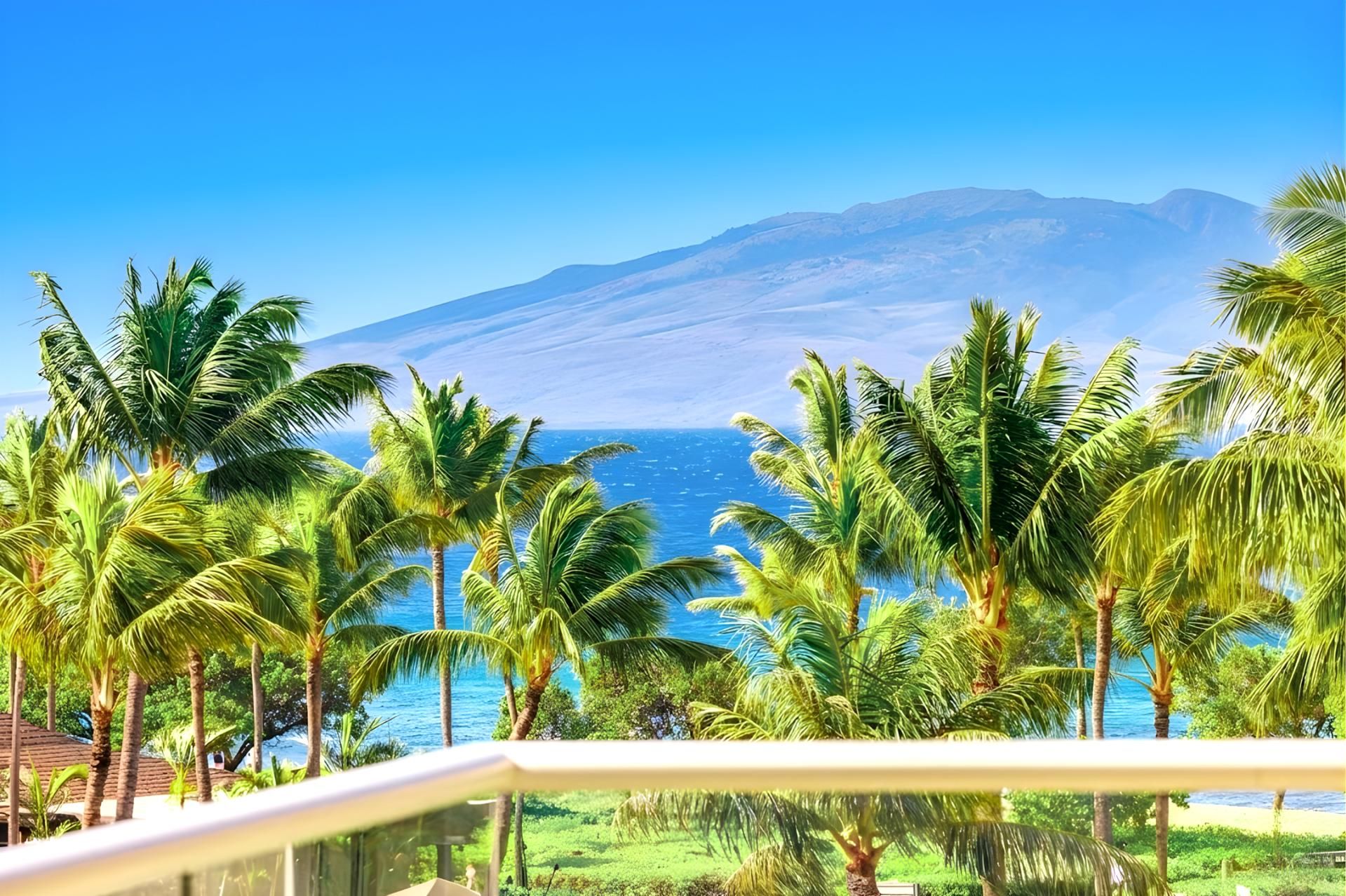 Un complexe hôtelier tropical, avec des palmiers, une vue sur l’océan et une montagne en arrière-plan.