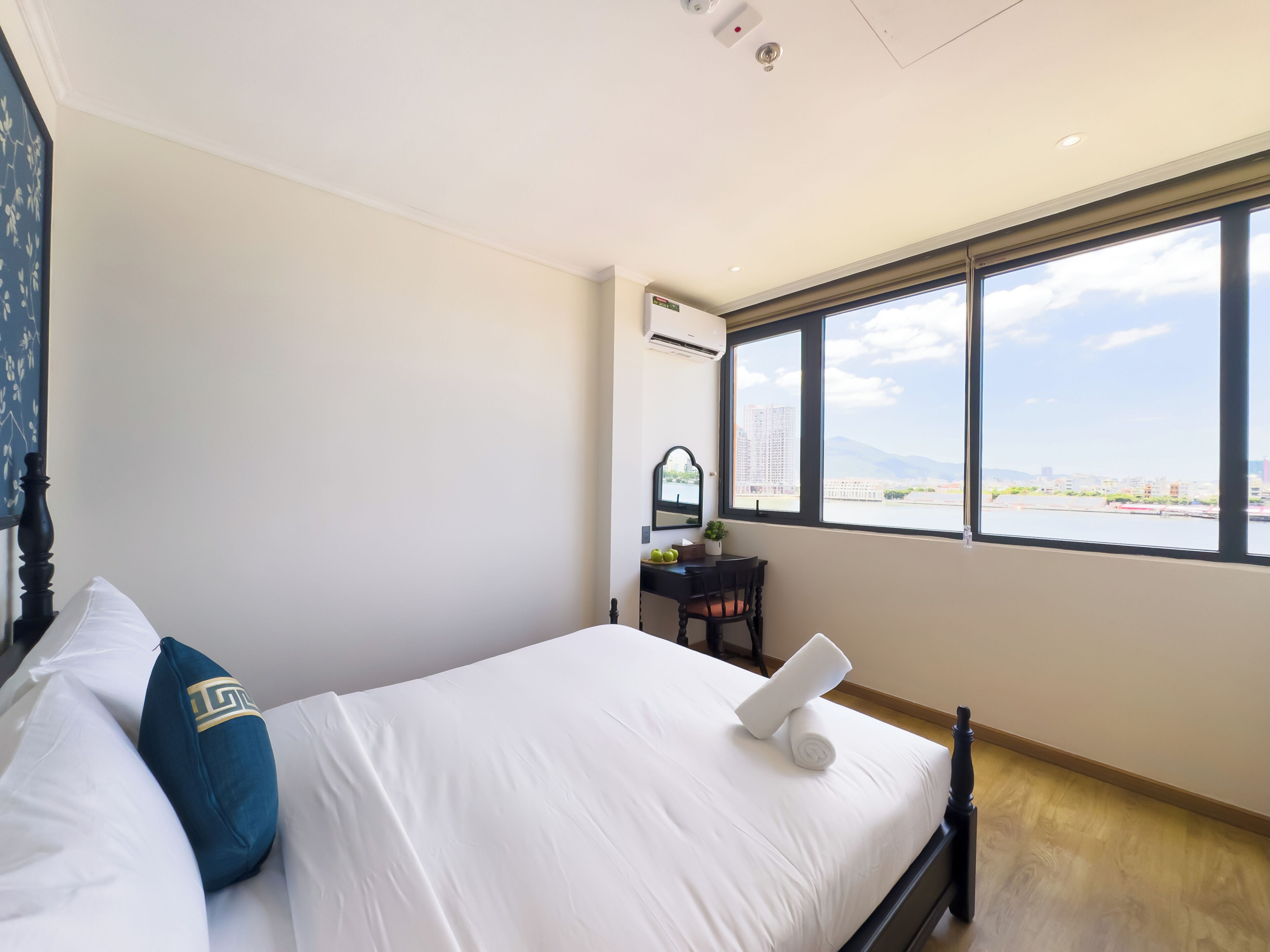 Een slaapkamer met een bed, een bureau, een stoel en een groot raam met uitzicht.