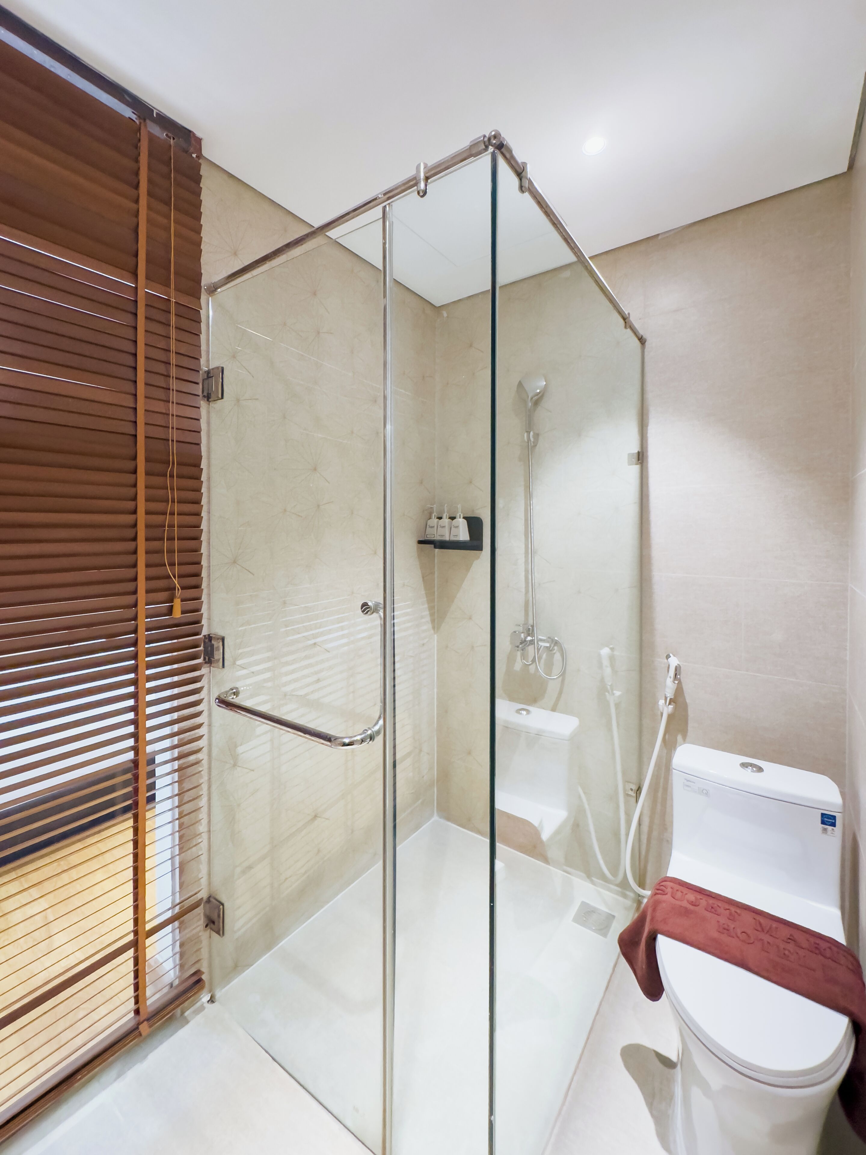 Un baño moderno con cabina de ducha de vidrio, un inodoro con toalla y un lavamanos.