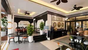 Un hall d’hôtel comprenant un comptoir d’accueil, un espace salon et un panneau indiquant le buffet.