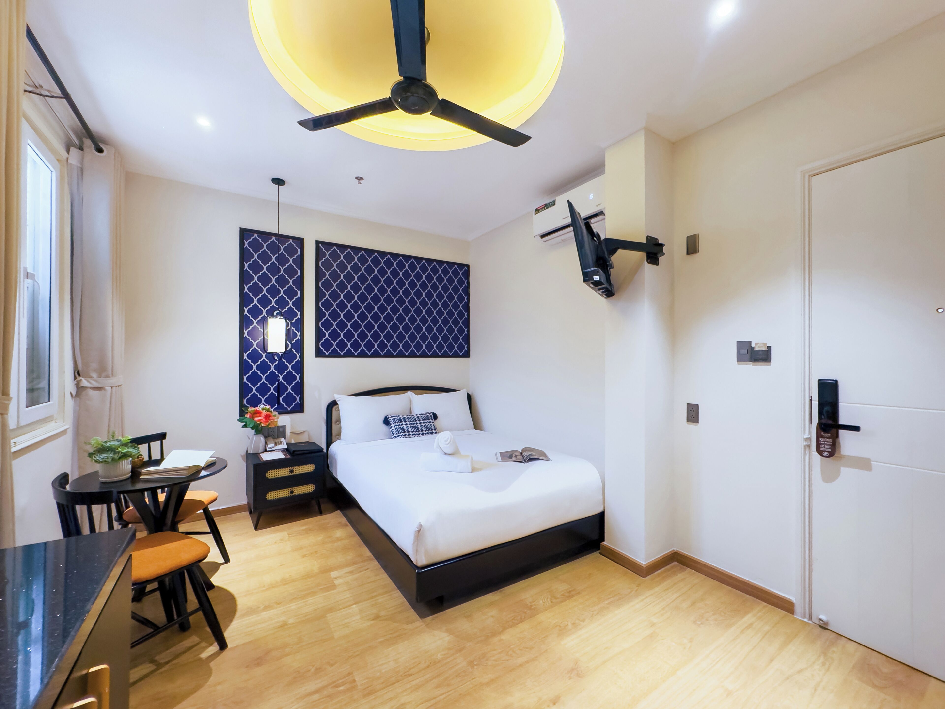 Ein modernes Hotelzimmer mit Bett, Nachttisch, Stuhl und Deckenventilator.