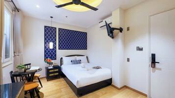 Ein modernes Hotelzimmer mit Bett, Nachttisch, Stuhl und Deckenventilator.