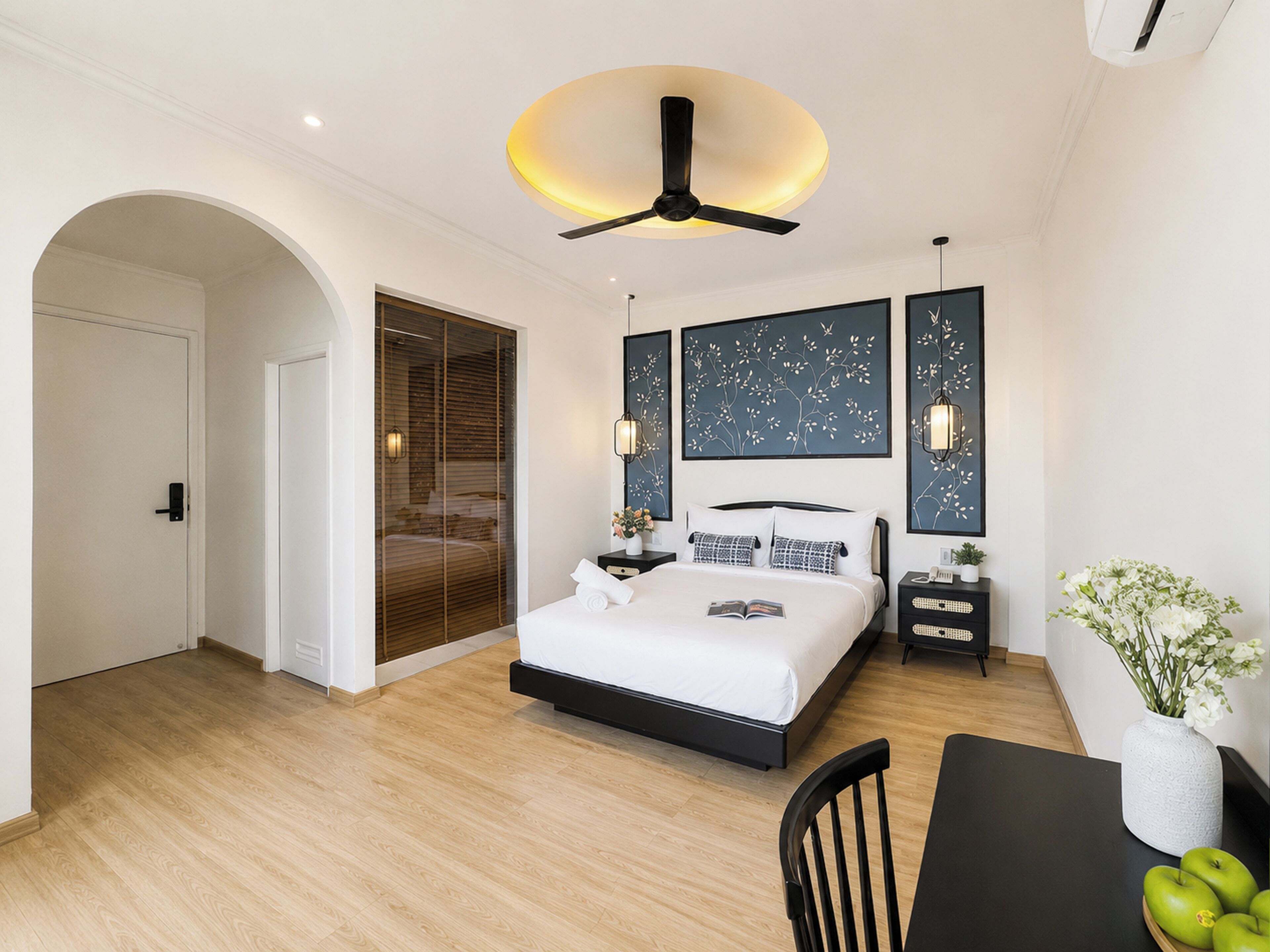 Un dormitorio moderno con cama, mesitas de noche, ventilador de techo y obras de arte en las paredes.