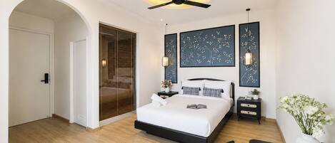Un dormitorio moderno con cama, mesitas de noche, ventilador de techo y obras de arte en las paredes.