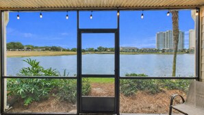 A room with a large window overlooking a lake, a chair, and a door.