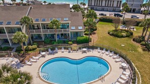 Uma piscina com design em formato de coração, rodeada por espreguiçadeiras e um cercado.
