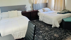 A hotel room with two beds, a nightstand, a desk, and a patterned floor. - Spacious and Comfy 2-bedroom condo with AC near UC Riverside (Riverside)