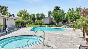 A swimming pool area with two pools, a stone deck, and surrounding greenery. - Spacious and Comfy 2-bedroom condo with AC near UC Riverside (Riverside)