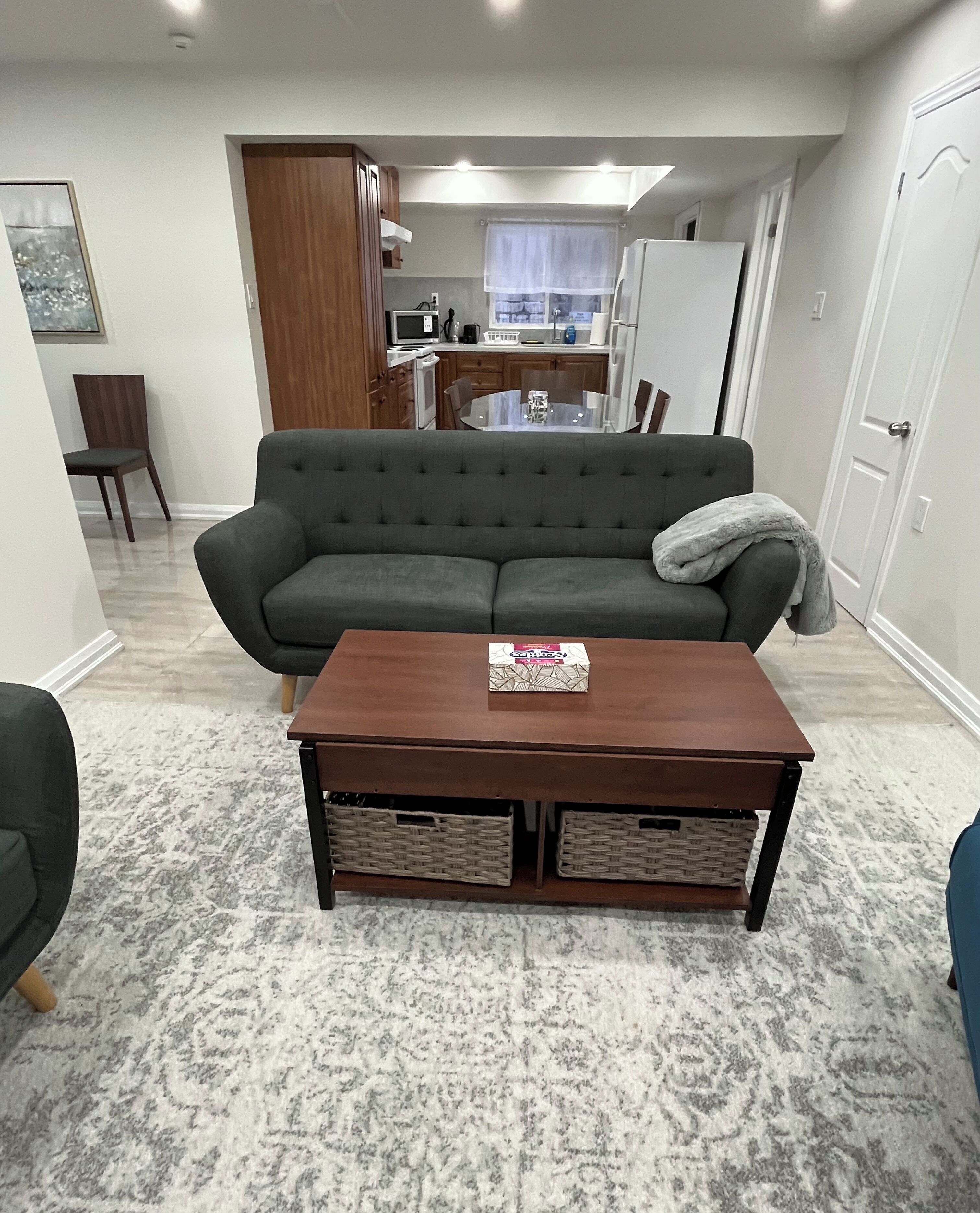 A living room with a sofa, a coffee table, and a dining table in the background.
