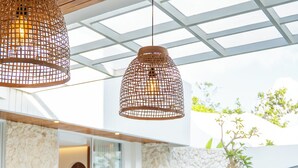 A dining area with a pool view, wooden table, and hanging wicker lamps. - Lomo Boutique Hotel & Villas, Uluwatu (Pecatu)