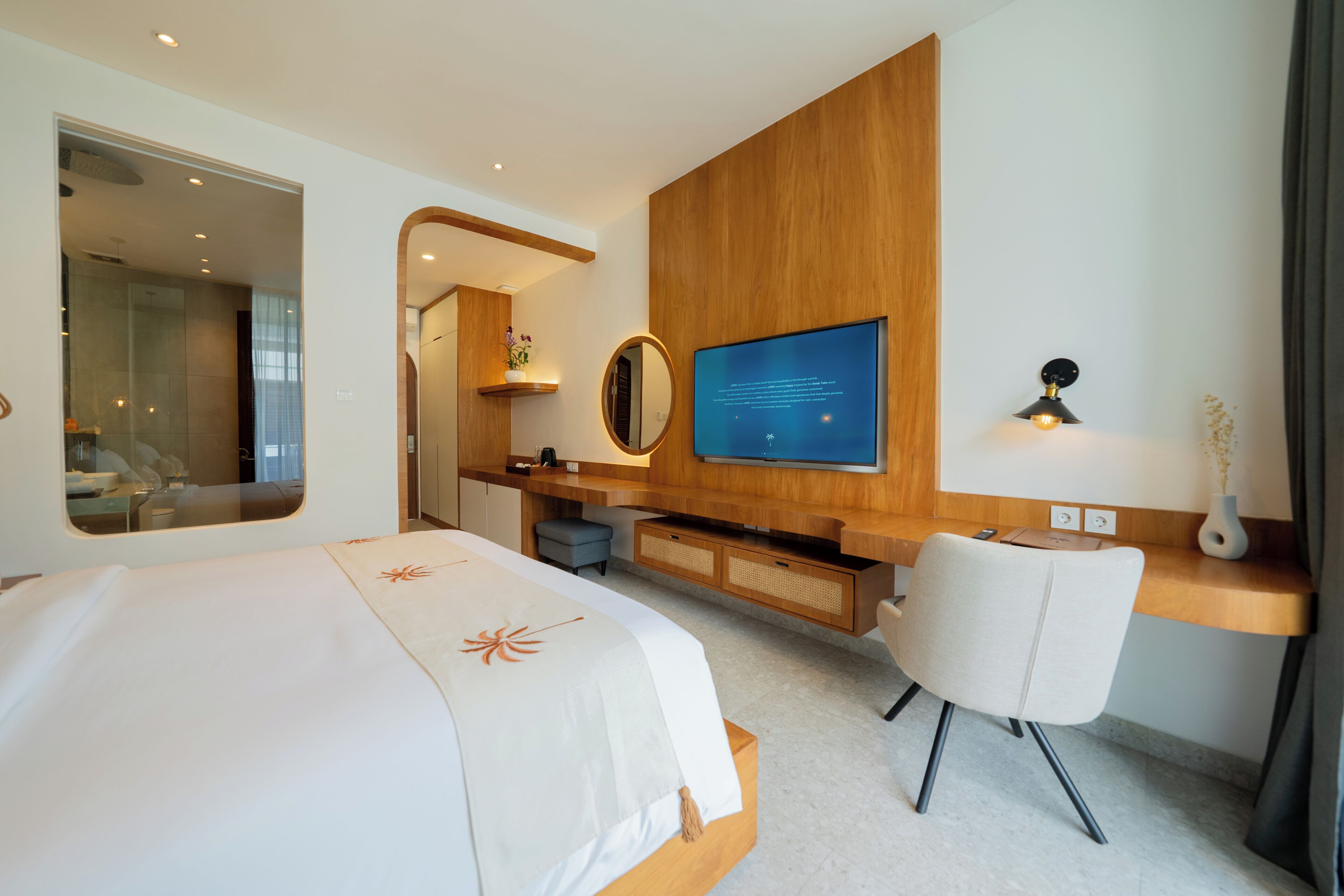 Une chambre d’hôtel moderne équipée d’un lit, d’un bureau, d’une télévision et d’un miroir.
