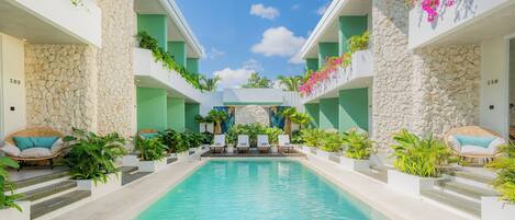 Zona de piscina con sillones de descanso y plantas en macetas.