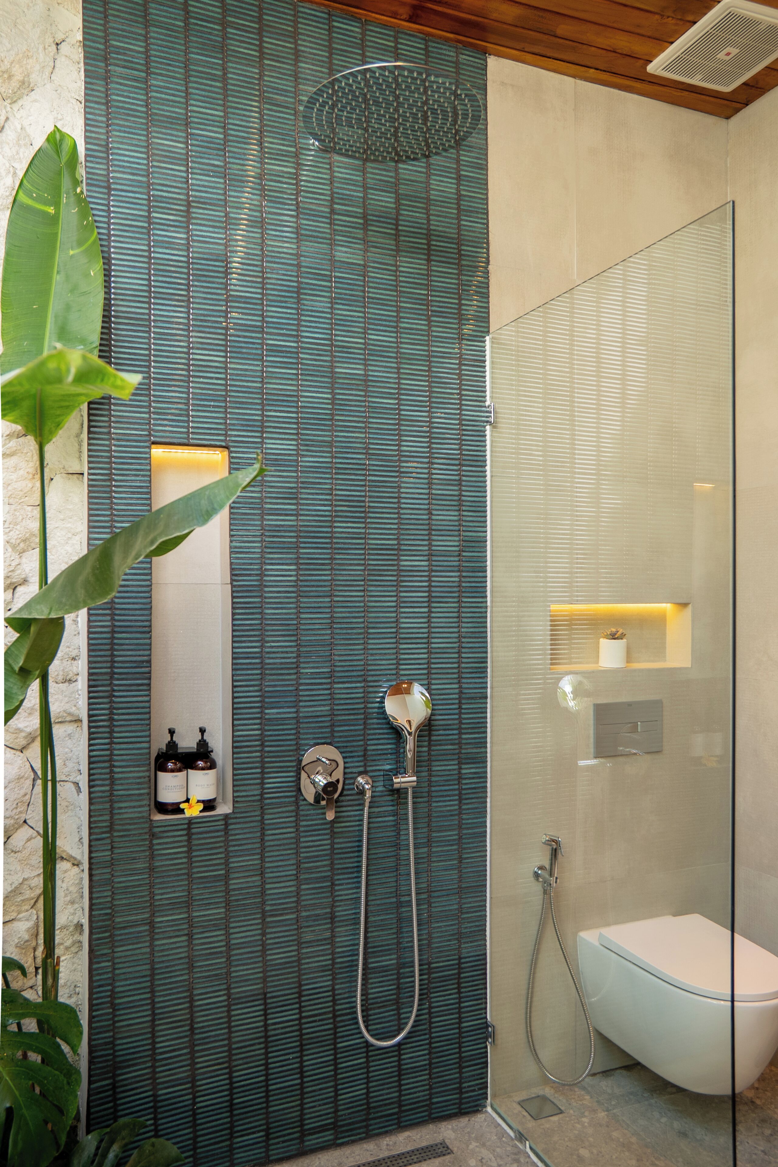 Ein modernes Badezimmer mit Duschkabine aus Glas, einer weißen Toilette und einem wandmontierten Waschbecken.