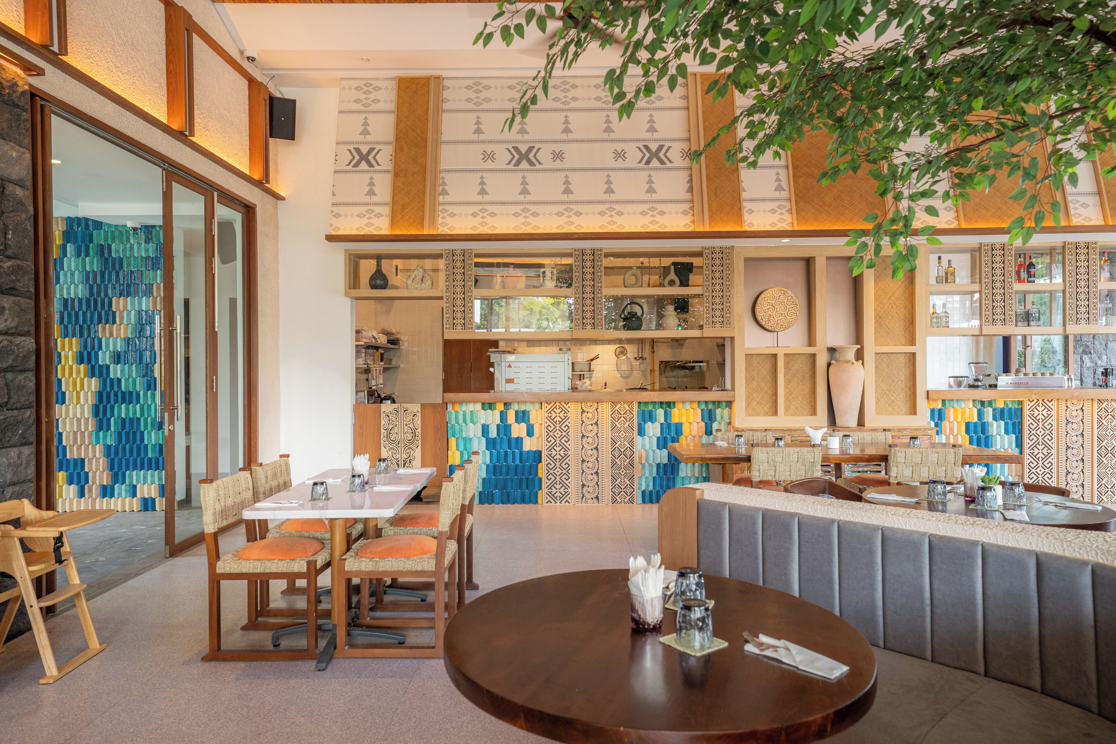 Un restaurante con una mesa redonda de madera, asientos y una pared decorativa.