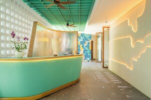 A reception area with a curved teal counter, a ceiling fan, patterned walls, and a modern design.