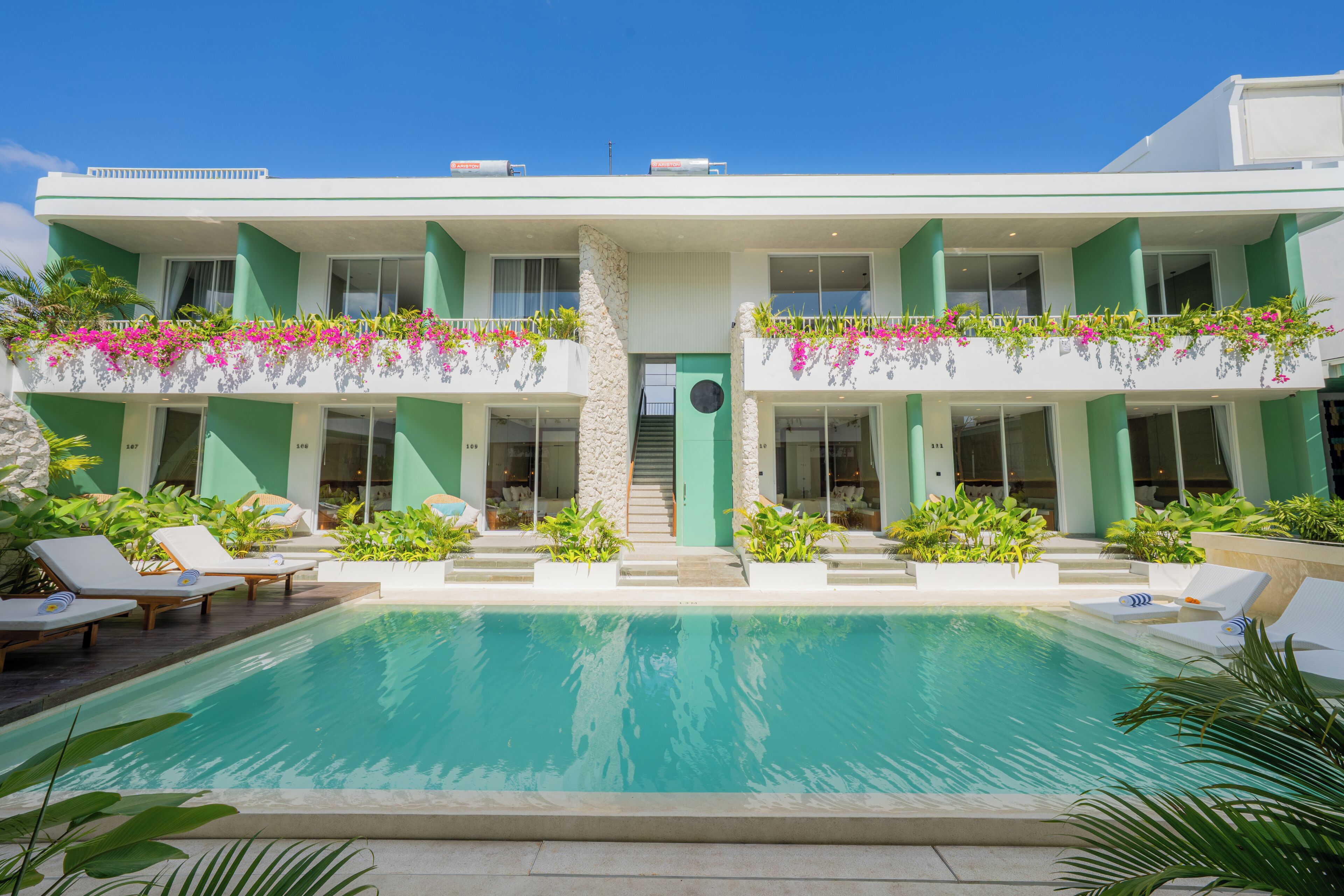 Un hotel moderno con piscina, asientos exteriores y exuberante vegetación.
