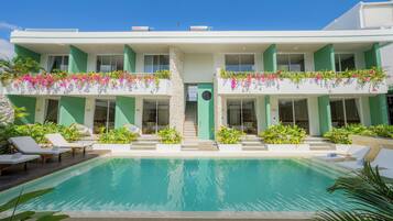 Un hotel moderno con piscina, asientos exteriores y exuberante vegetación.