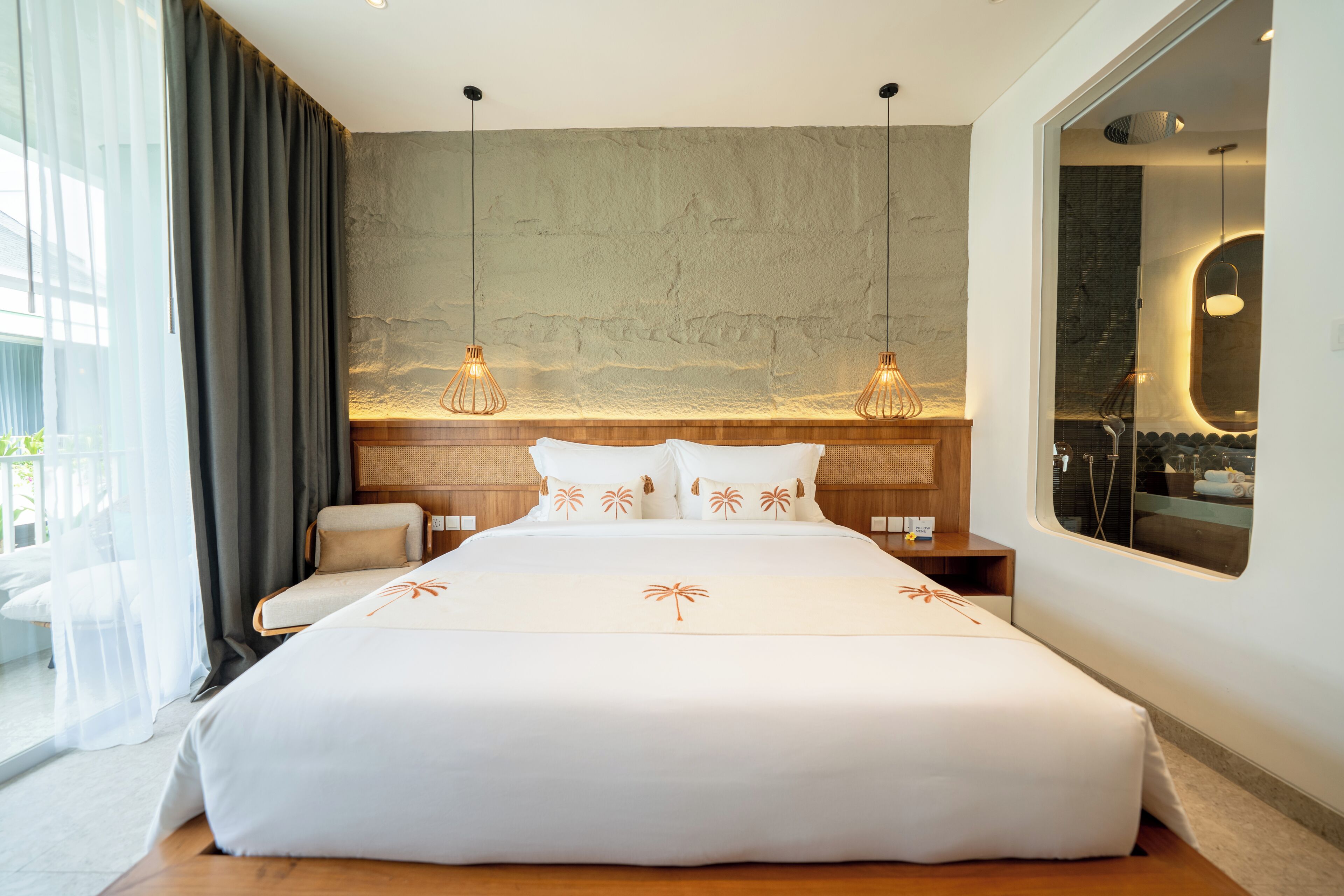 Ein modernes Hotelzimmer mit einem großen Bett, einem Holz-Kopfteil, einem großen Fenster und Blick ins Freie.